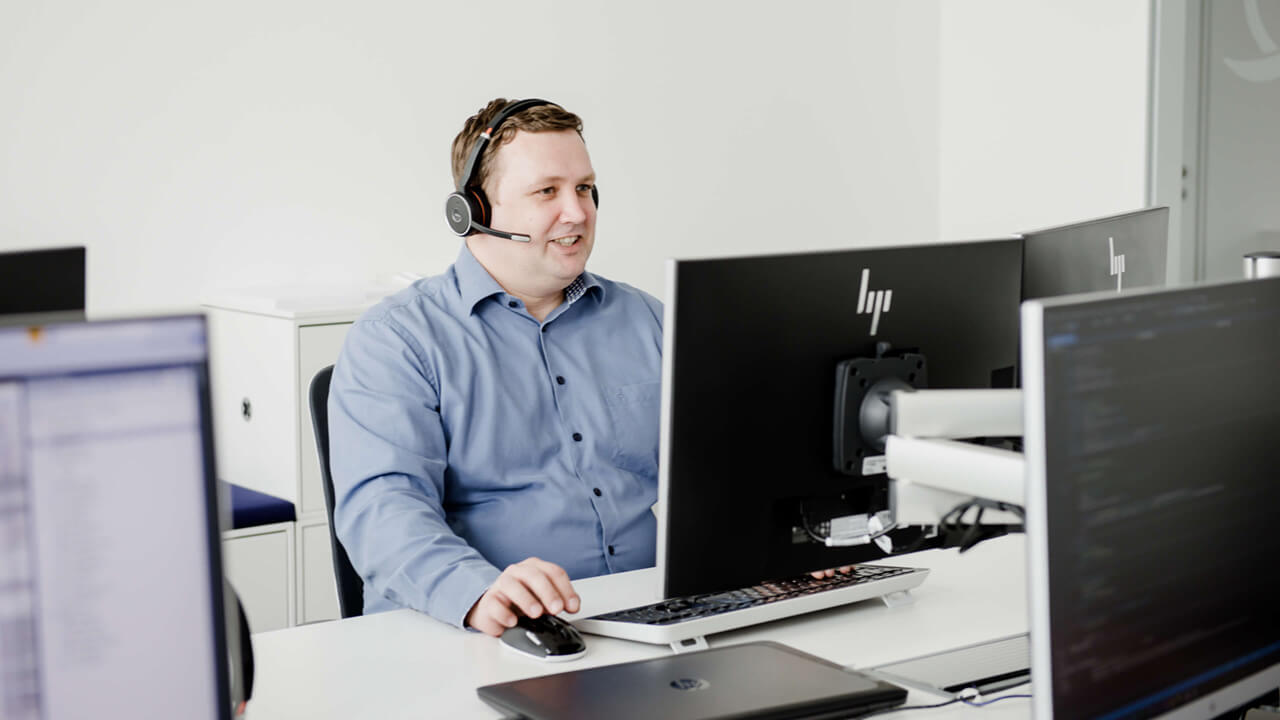 IT Service Desk Mitarbeiter am Telefonieren vor einem Bildschirm