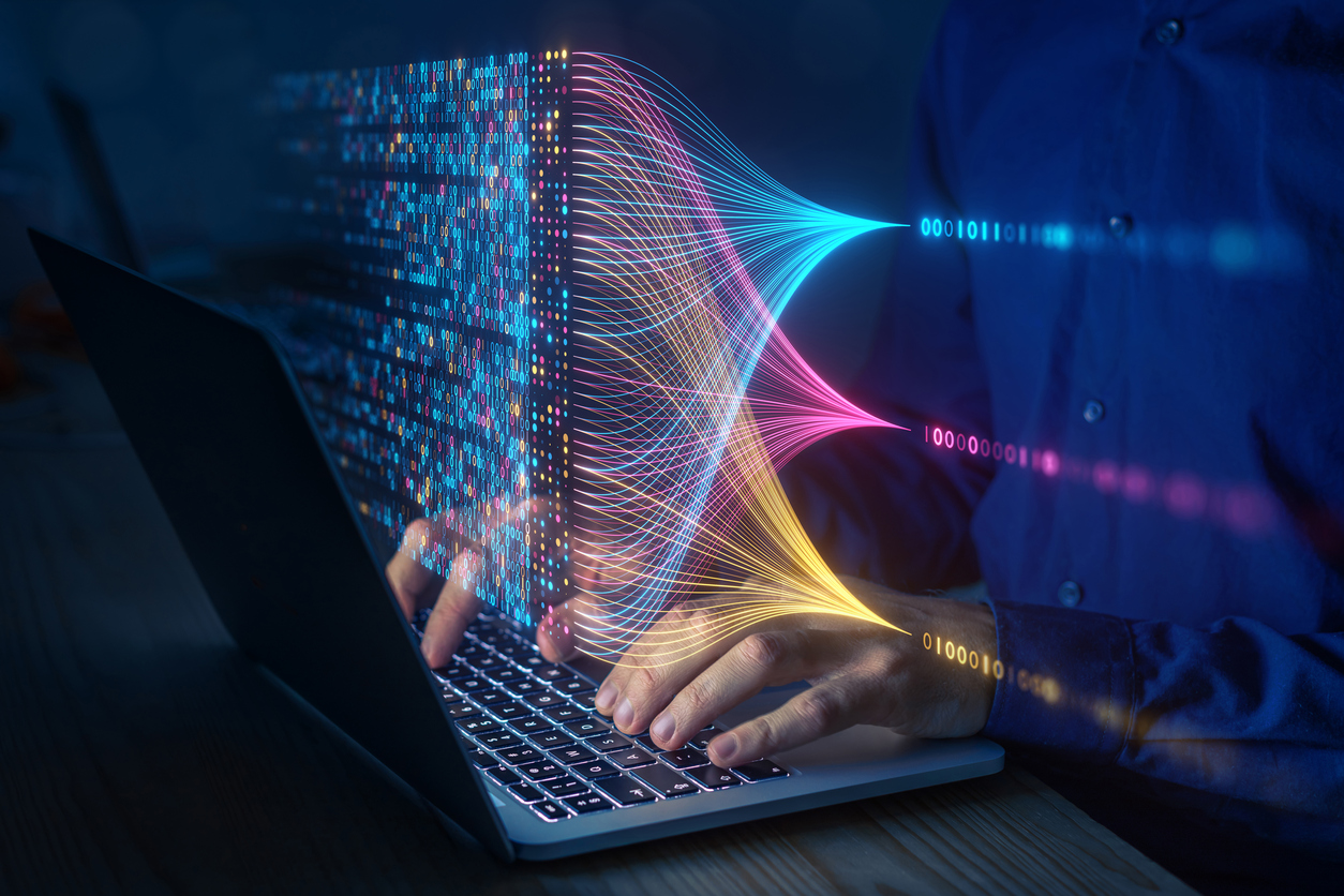 Person tippt am Laptop und es werden Datenströme eingeblendet