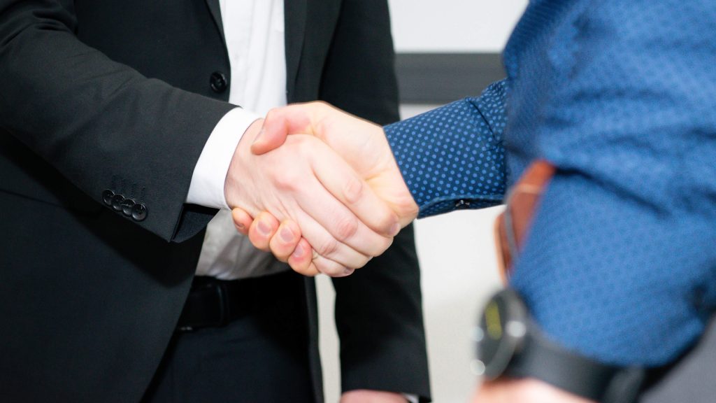 Ein Mitarbeiter macht einen Handschlag mit einem Kunden als Veranschaulichung für den Managed Services Prozess